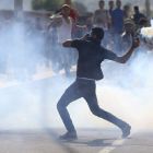 Un palestino lanza gas lacrimógeno contra soldados israelíes.