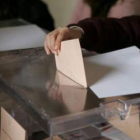 Una mujer introduce su voto en una urna durante unas elecciones.