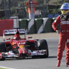 El piloto español Fernando Alonso espera en la pista la ayuda de la asistencia tras pararse el nuevo monoplaza F14T de la escudería Ferrari a la salida de la curva "Peluqui".