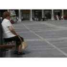 Una señora descansa en un banco de la Plaza Mayor de León.