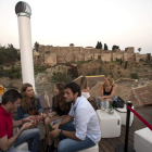 Un grupo de personas en la terraza del Alcazaba Premium Hostel con vistas a este monumento malagueño.
