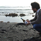 Rubén G. Franco en una playa de lava negra de Canarias con una botella de su marca, La Deriva (www.laderivawine.com).