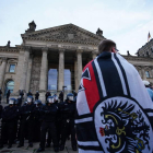 Un manifestante delante del edificio del Reichstag en Berlín con una bandera imperial. CLEMENS BILAN