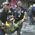 Dos manifestantes ayudan a un hombre herido por el estallido de una granada durante el quinto día de bloqueo en Bangkok.