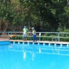 Dos técnicos de piscinas limpian el recinto antes de la hora de apertura al público
