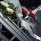 Cuatro rosas blancas con la leyenda «Para cuatro ángeles» en la puerta del campo de béis
