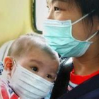 Una madre protege a su bebé con una mascarilla del virus de la neumonía, en un tren de Hong Kong