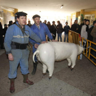 Dos matarifes con un cerdo de cartón irrumpen entre quienes esperan el reparto de chichas.