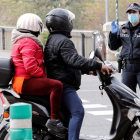 Una agente de la Policía Local de Valencia pregunta a dos personas que circulan en moto. JUAN CARLOS CÁRDENAS
