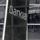 Un protesta frente a la sede de Bankia, reflejada en la cristalera del edificio.