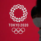 Fotografía de archivo de personas con tapabocas pasando frente a un cartel con la imagen de los Juegos Olímpicos Tokio 2020 el 15 de julio de 2020 . KIMIMASA MAYAMA