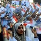 Mujeres iraquíes ondean banderas en un mítin de apoyo a Sadam Husein ayer en Badgad, antes de votar