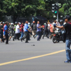 Un hombre armado apunta hacia un centro comercial mientras decenas de personas corren, en el centro de Yakarta.
