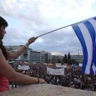 Una mujer ondea una bandera griega en una protesta.