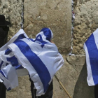Jóvenes israelís se cubren con la bandera de Israel junto a un untraortodoxo frente al Muro de las Lamentaciones. /