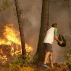 Una persona arroja agua en el incendio que afectó el domingo a la zona de Zamanes, cerca de Vigo.