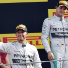 Hamilton celebra su victoria en Monza bajo la mirada de su compañero Rosberg.