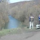 Dos personas observan el lugar concreto de la carretera por el que el vehículo se precipitó al río