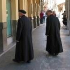 Dos sacerdotes pasean bajo los soportales de la plaza Mayor de Astorga