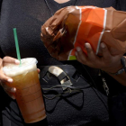 Una mujer pasea por la calle con comida y una bebida de refresco gigante. JUSTIN LANE