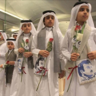 Niños qatarís con flores e imágenes del emir Al Thani reciben a ciudadanos de Kuwait y Omán, países que no se han sumado al boicot, en el aeropuerto de Doha.