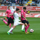 Eneko Capilla disputa un balón a dos jugadores rivales.