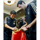 Juan Mata y Sergio Busquets firman una bandera española tras la rueda de prensa que ofrecieron hoy e