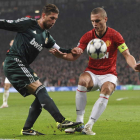El defensa del Real Madrid, Sergio Ramos, disputa un balón con el fornido jugador serbio del Manchester United, Nemanja Vidic.