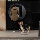 Una mujer saca dinero de un cajero y pasea a su perro en Barcelona. ENRIC FONTCUBERTA