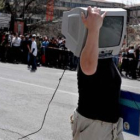 Un hombre lleva una televisión que ha podido recuperar de entre los restos de su vivienda