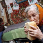 Una anciana prueba un pan ante la presencia de su marido en su casa de Ucrania.