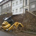 La máquina elevadora quedó tendida sobre el asfalto tras derrumbarse el muro.