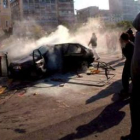 Un grupo de manifestantes junto a un coche incendiado durante el tercer día de graves disturbios en