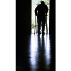 Un anciano camina con ayuda en una residencia.