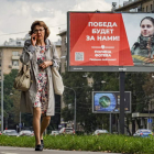 Una mujer rusa pasa ante un cartel que anuncia la mili con el lema «¡La victoria será nuestra!». YURI KOCHETKOV