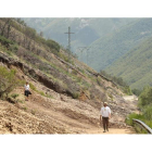 Dos vecinos de Valseco, ayer, saliendo del pueblo andando tras una travesía de tres kilómetros y medio. En la imagen se pueden ver los efectos del derrumbre a lo largo de varios metros.L. DE LA MATA