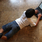 Un niño navega por internet tumbado en el suelo de su casa.