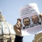 Un miembro de la Federación Nacional de la Prensa Italiana (FNSI) sostiene un cartel con la imagen de los periodistas italianos Gianluigi Nuzzi y Emiliano Fittipaldi, durante una sesión del proceso conocido como Vatileaks2
