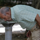 Un hombre bebe agua en una fuente pública en León. FERNANDO OTERO