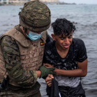 Un soldado del Ejército ayuda a un menor a salir del agua en la playa de El Tarajal. BRAIS LORENZO