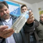 Manuel Gancedo muestra un botella con agua sucia de la red de Montes