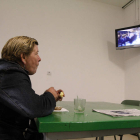 Una de las usuarias del centro de día toma un café mientras mira el televisor.