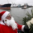 Un hombre vestido de Santa Claus observa el precio de un árbol de Navidad, uno de los gastos asumido
