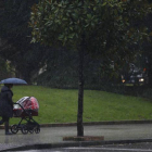 Una mujer pasea con un carrito de bebé en medio de una fuerte racha de viento y lluvia