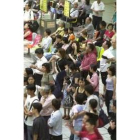 Decenas de viajeros, ya sin máscaras, esperan el tren en Taipei