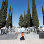 Una mujer pasea ayer por el cementerio de Cacabelos resguardada del sol por un paraguas ante los famosos cipreses. LUIS DE LA MATA