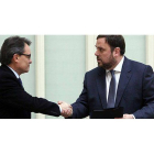 Artus Mas y Oriol Junqueras se saludan tras la firma del acuerdo en el Parlament.