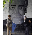 Dos mujeres conversan en la calle ante un graffiti. MIGUEL LEMUS