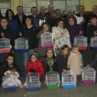 Los ganadores del concurso ornitológico posan con los niños premiados en el certamen de dibujo, que recibieron un canario.