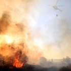 Un helicóptero vierte agua en un momento en el que las llamas amenazan las casas de Molina.
